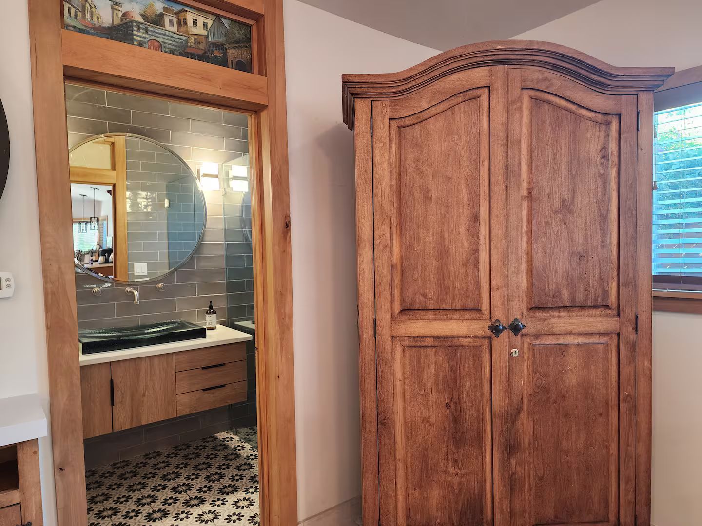 Casa de banho com toucador de madeira, espelho e lavatório.