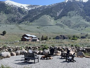 A rural landscape with a gravel patio, Adirondack chairs, and a view of a mountain range.