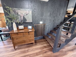 Une commode en bois avec des tiroirs, un tableau encadré et un vase avec une plante.