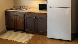 Una cocina con armarios de madera, un refrigerador blanco, un microondas y una lámpara colgante.