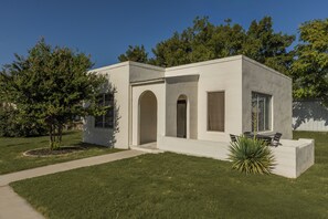 Une maison moderne de plain-pied, dotée d’un toit plat, d’un patio couvert et d’une pelouse bien entretenue.