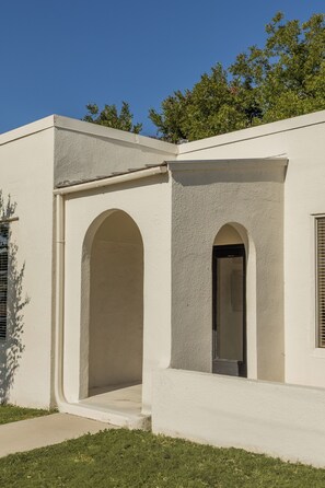 A building with a flat facade, two arched doorways, and a window with horizontal blinds.