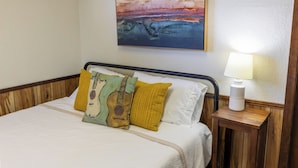Una habitación de hotel con una cama, una mesita de noche con una lámpara y un cuadro en la pared.