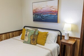 Une chambre d’hôtel avec un lit, une table de chevet avec une lampe et un tableau au mur.
