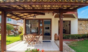 A covered outdoor area with a table and chairs, a stone wall, and a vehicle parked outside.