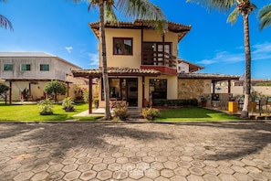 A two-story house with a stone facade, a tiled roof, and a paved driveway.