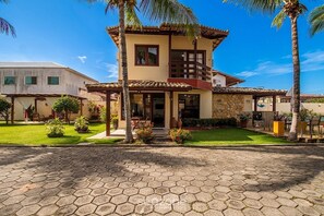 A two-story house with a stone facade, a tiled roof, and a paved driveway.