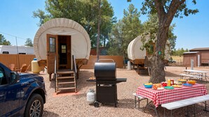 Un campeggio con strutture coperte, un barbecue e un tavolo da picnic con cibo.