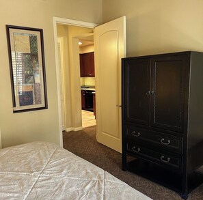 Quarto com cama, guarda-roupa e porta de acesso a uma cozinha.
