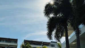 A modern hotel with multiple floors, a well-maintained lawn, and palm trees. - Beautiful 2 Bedroom with A/C, BBQ, and Pools (Nuevo Nayarit)