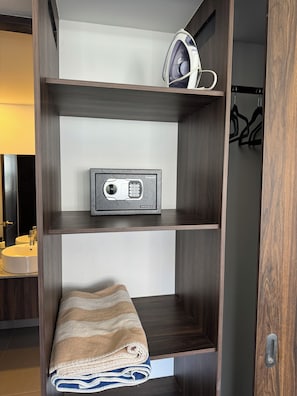 A wooden wardrobe with a built-in safe, a hanging iron, and a folded towel. - Beautiful 2 Bedroom with A/C, BBQ, and Pools (Nuevo Nayarit)
