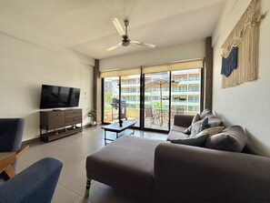Ein modernes Wohnzimmer mit Flachbildfernseher, einer Couch, einem Couchtisch und einem Deckenventilator.
