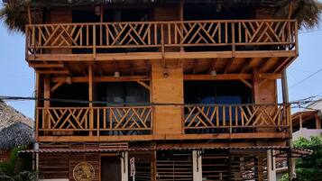 Un edificio de madera de dos pisos con techo de paja, un balcón con barandillas de madera y un letrero que dice 'LA PUNTA'.