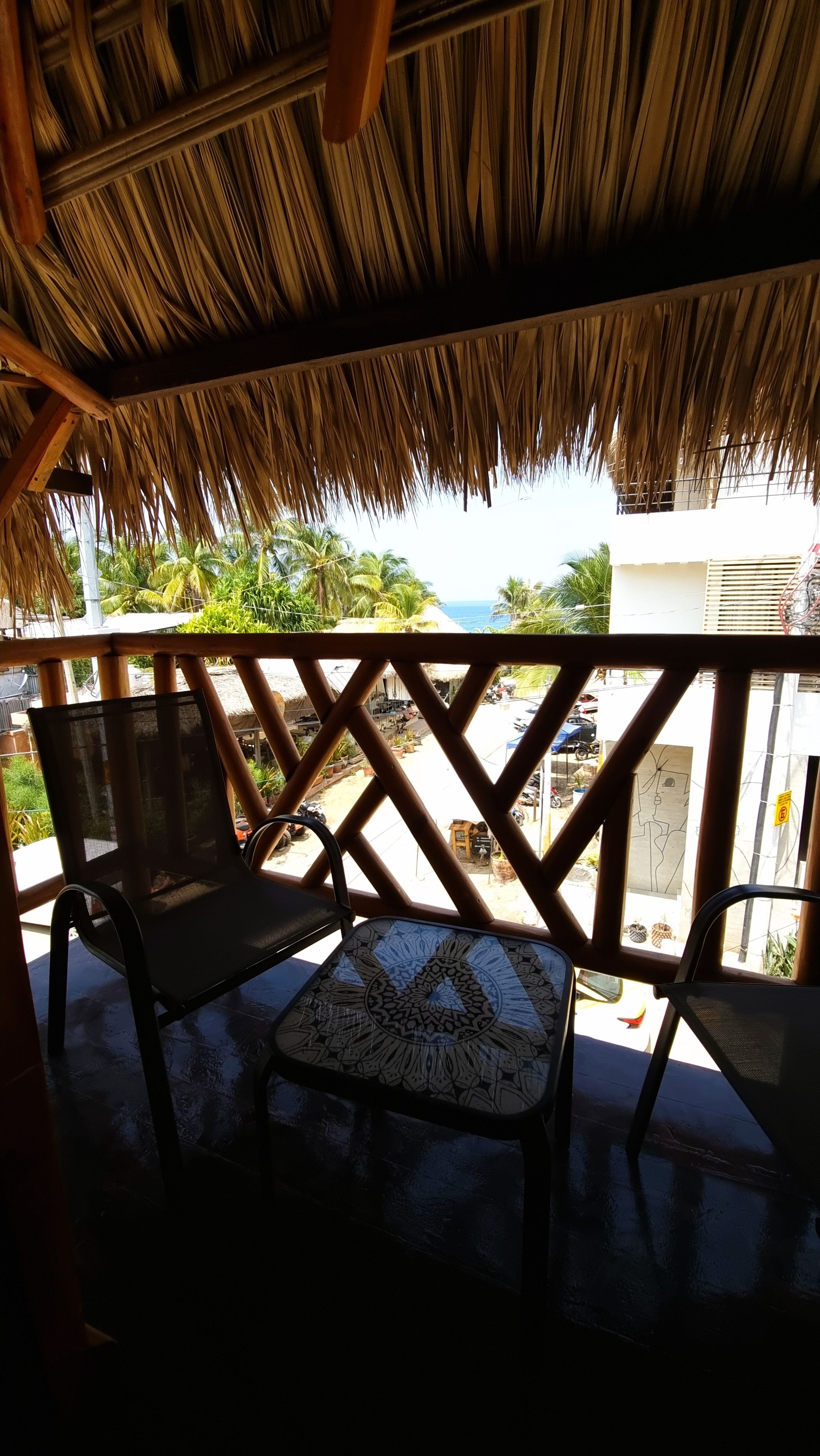 A covered outdoor seating area with a thatched roof, a table, and chairs.