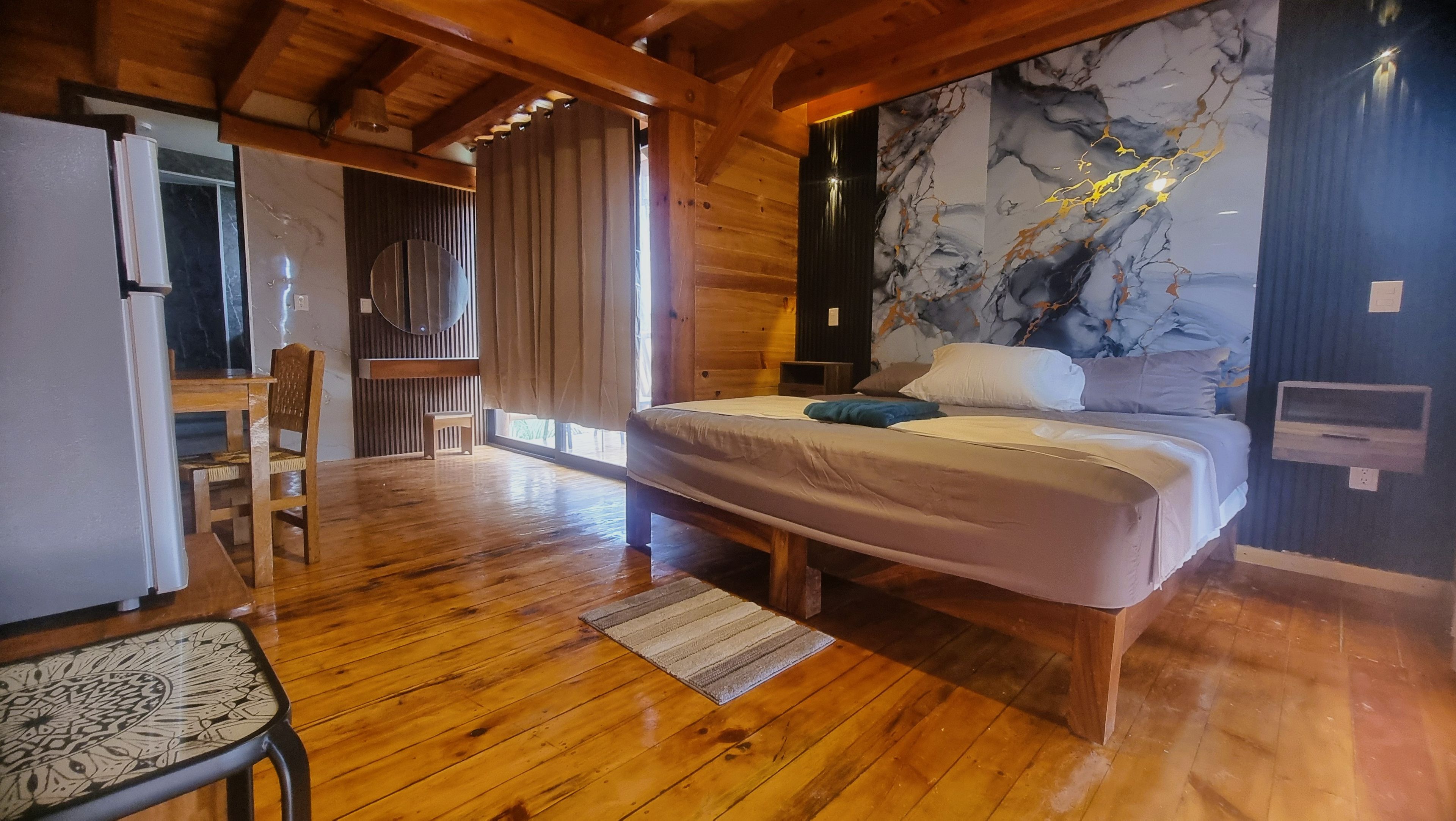 A wooden-framed bedroom with a bed, a desk, and a chair.