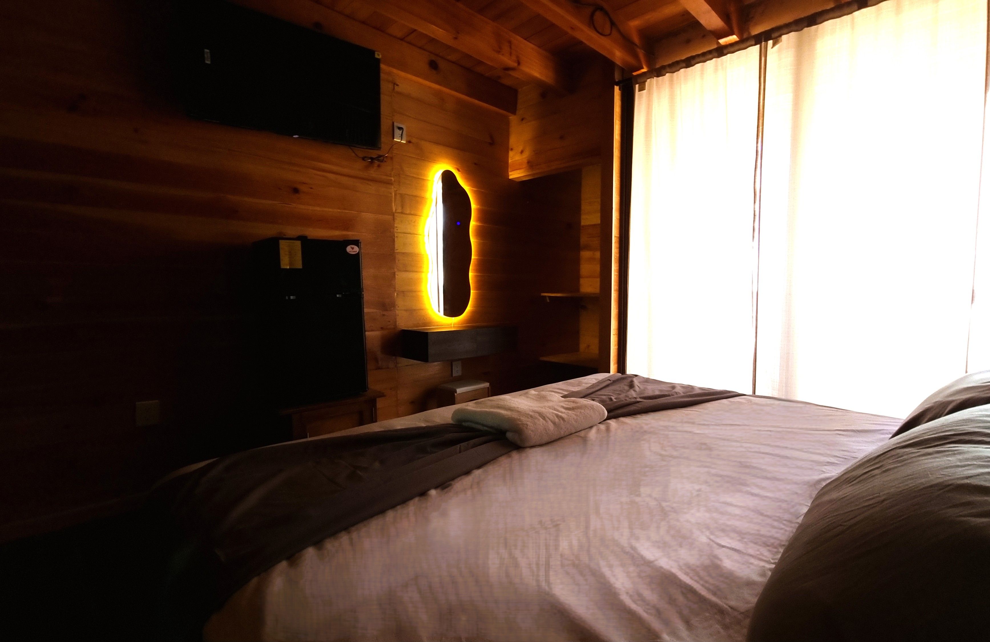 Una habitación con una cama, un televisor y una lámpara fijada a la pared.