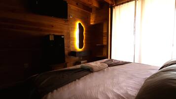 Una habitación con una cama, un televisor y una lámpara fijada a la pared.
