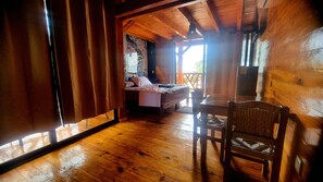 Interior de una cabaña de madera con una cama, una mesa y una silla.