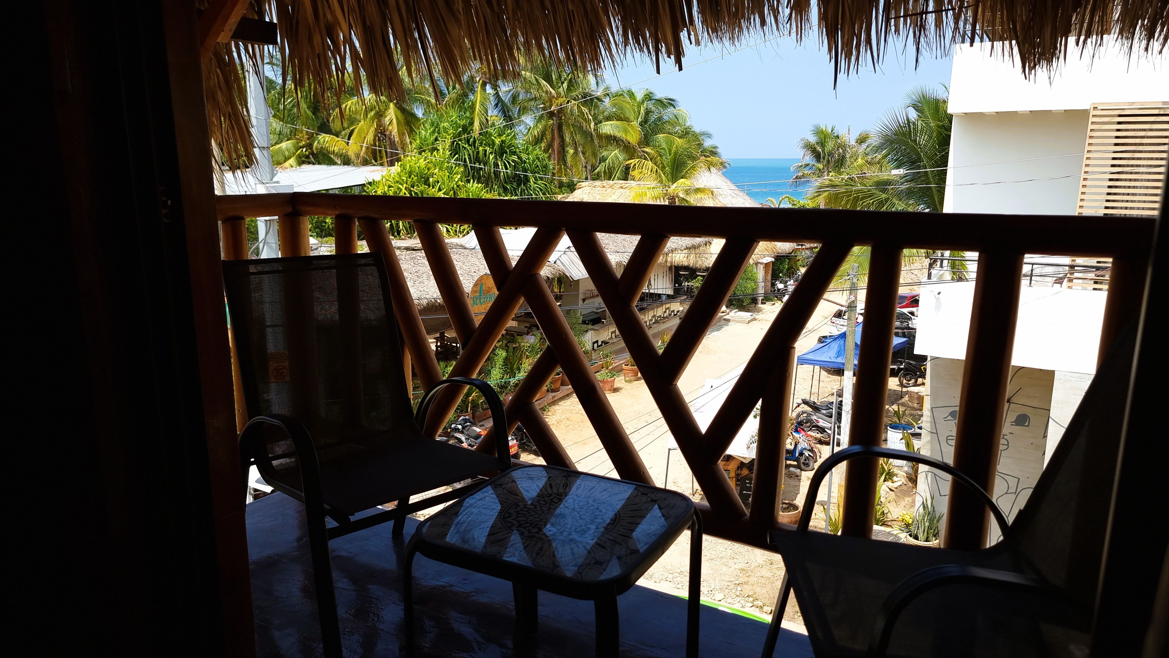 Un balcón con vista al mar, amueblado con dos sillas y una mesa.