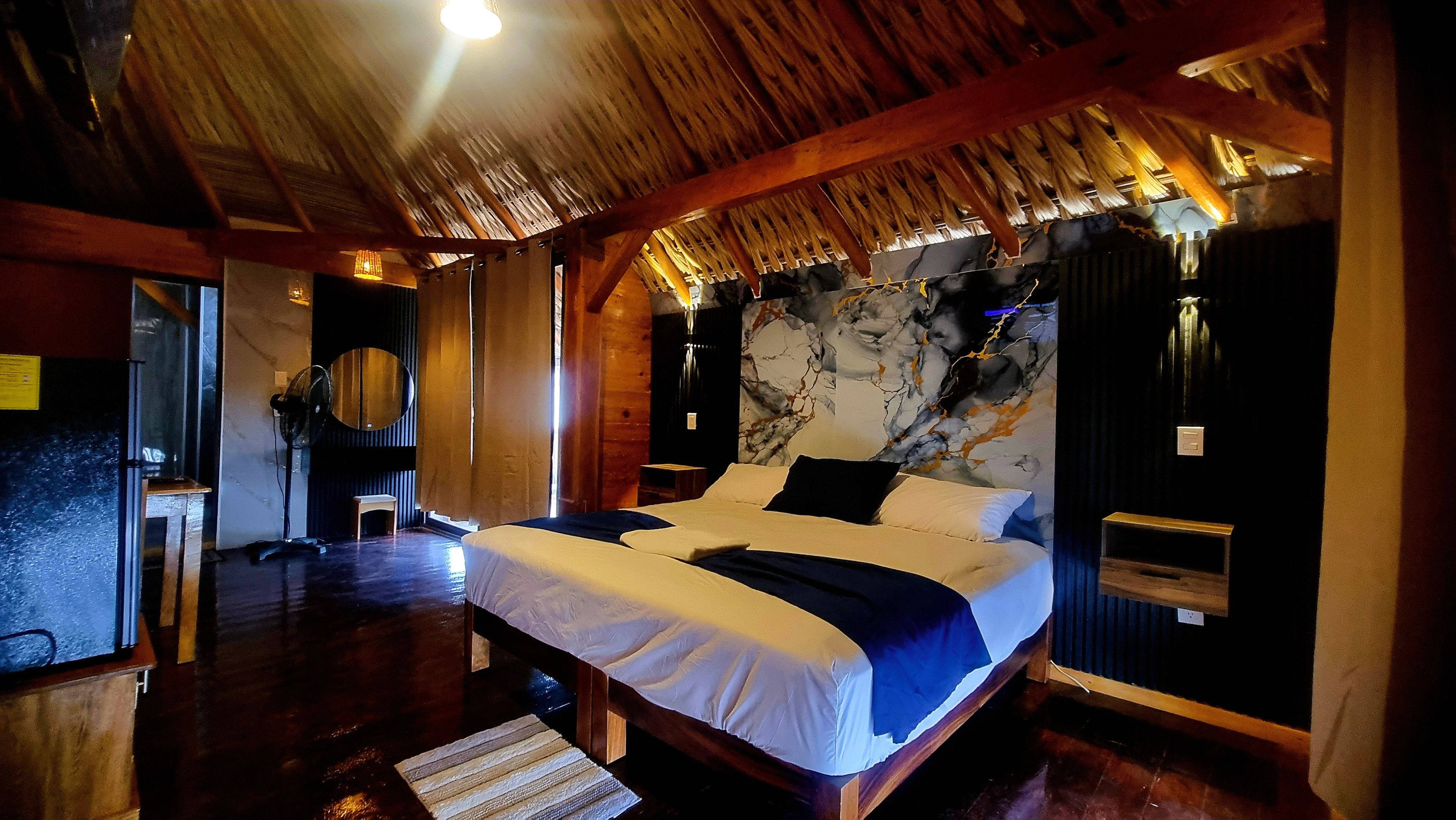 A room with a bed, a mirror, a small table, and a wall with a marble-like design.