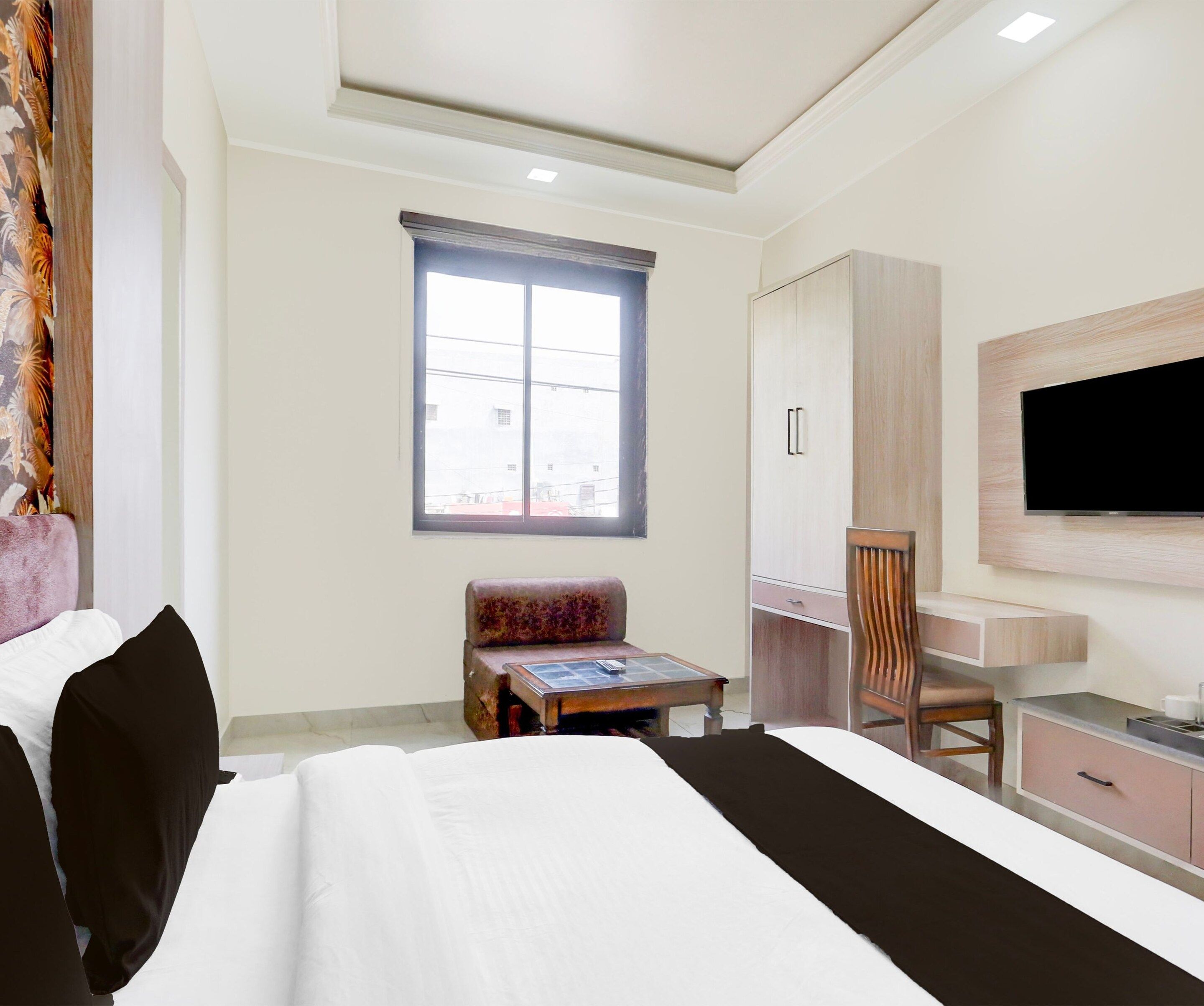 A hotel room with a bed, a desk, a chair, a television, and a window.