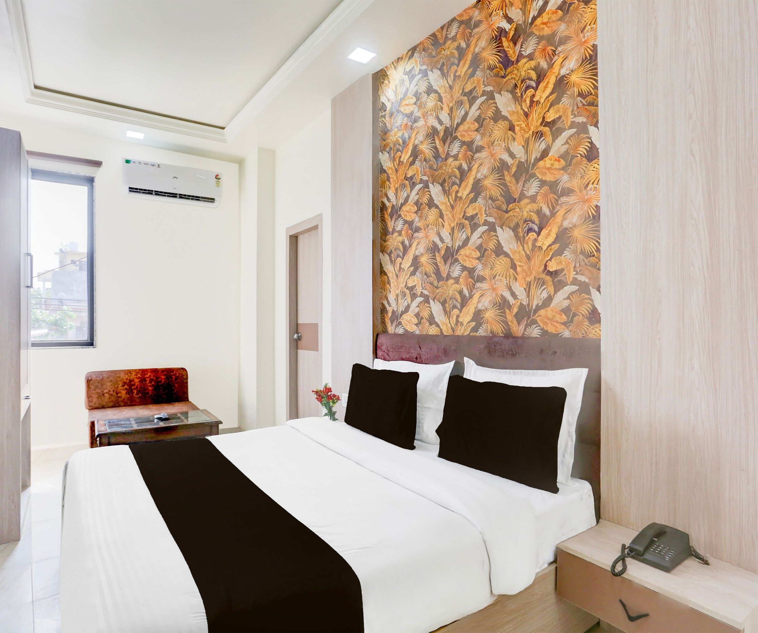 Una habitación de hotel con una cama, una mesita de noche con teléfono y un equipo de aire acondicionado instalado en la pared.