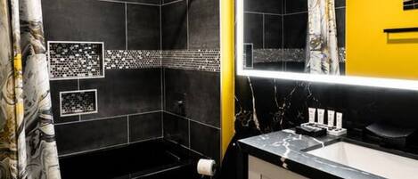A modern bathroom with a black and yellow color scheme, a large mirror, and a toilet.