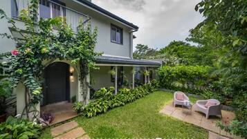 A house with a covered porch, a lawn, and two outdoor seating areas.