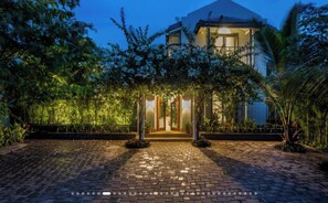 Una casa con vialetto lastricato, circondata dal verde e un cielo sereno.