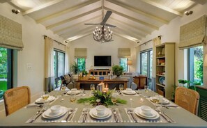 A dining area with a high ceiling, chandelier, and a television in the background. - French Villa with Private Pool (Awas)