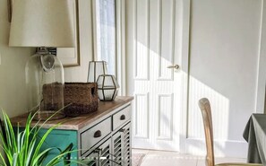 Habitació amb un armari de fusta, una làmpada, una cistella de vimet i una cadira.