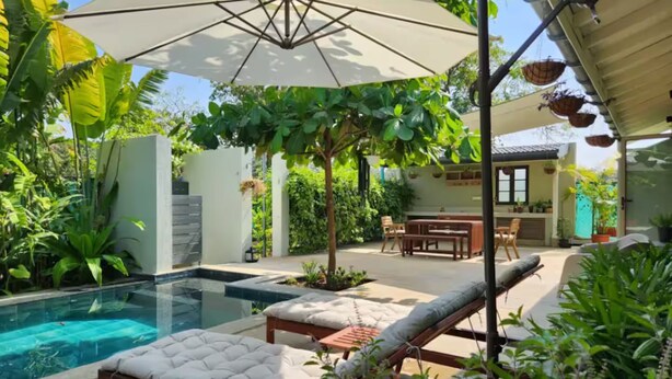 A pool area with lounge chairs and umbrellas, surrounded by lush greenery. - French Villa with Private Pool (Awas)