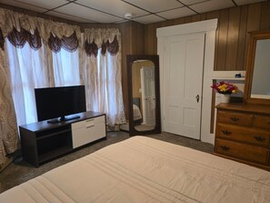 Habitació d'hotel amb llit, televisió a una petita taula, mirall, armari i porta.