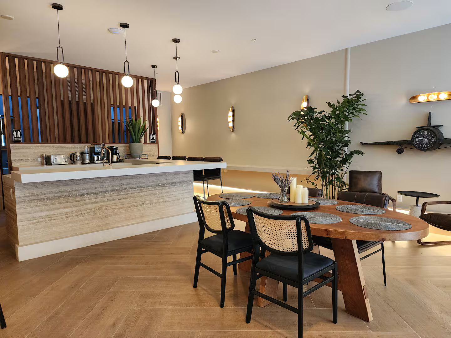 Une cuisine moderne avec un îlot central, un coin repas avec des chaises et une horloge au mur.