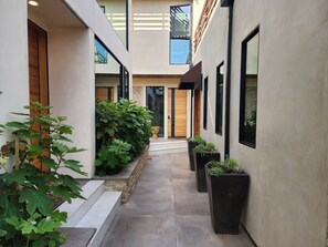 A narrow, covered walkway with potted plants and a wooden door at the end. - Luxury Studio Lounge at Jackson Market (Culver City)