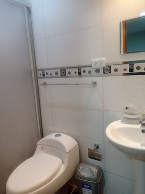 Une salle de bain équipée de toilettes, d’un lavabo et d’une poubelle.