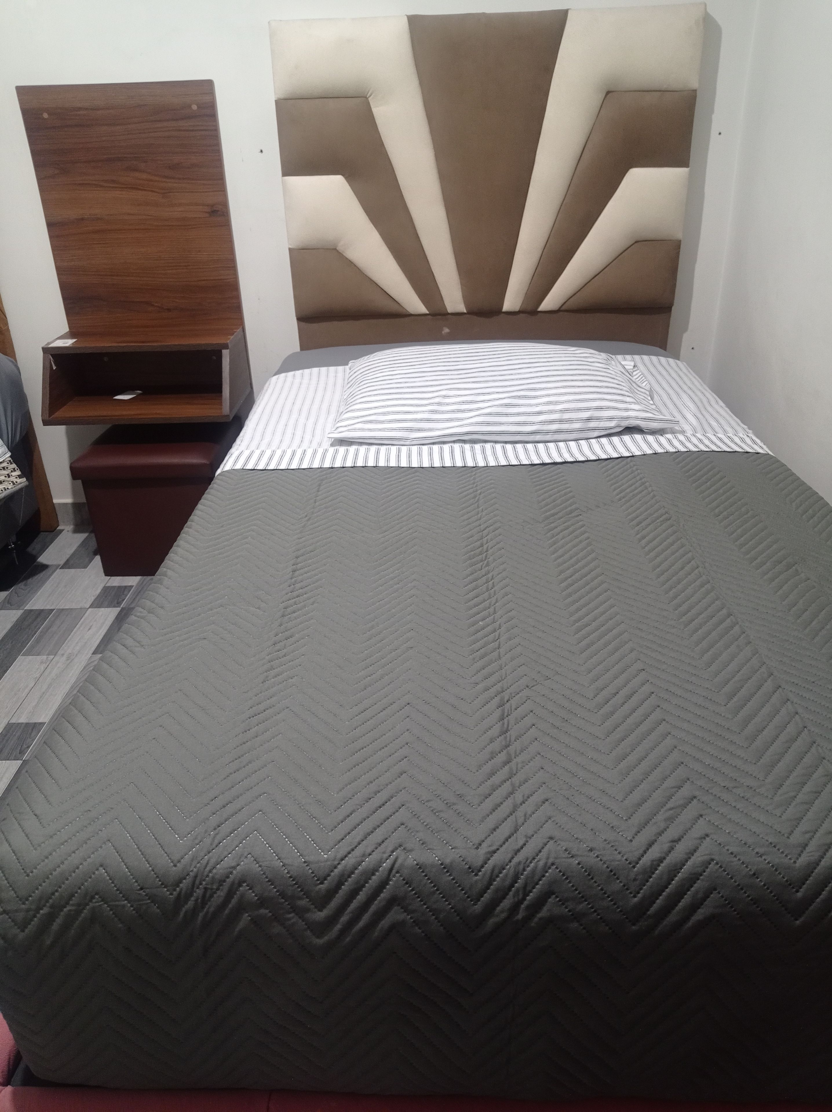 Un lit doté d’un matelas à motifs chevrons, d’un oreiller à rayures et d’une tête de lit au motif géométrique.