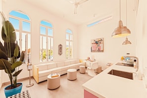 A bright, modern living room with a large window, a sofa, a dining table, and a kitchen area. - BIKINI (Willemstad)