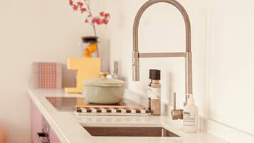 A kitchen with a modern faucet, a pot on the counter, and a bottle of hand soap.