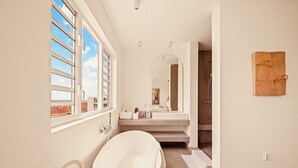 A modern bathroom with a freestanding bathtub, a large mirror, and a shower area. - BIKINI (Willemstad)
