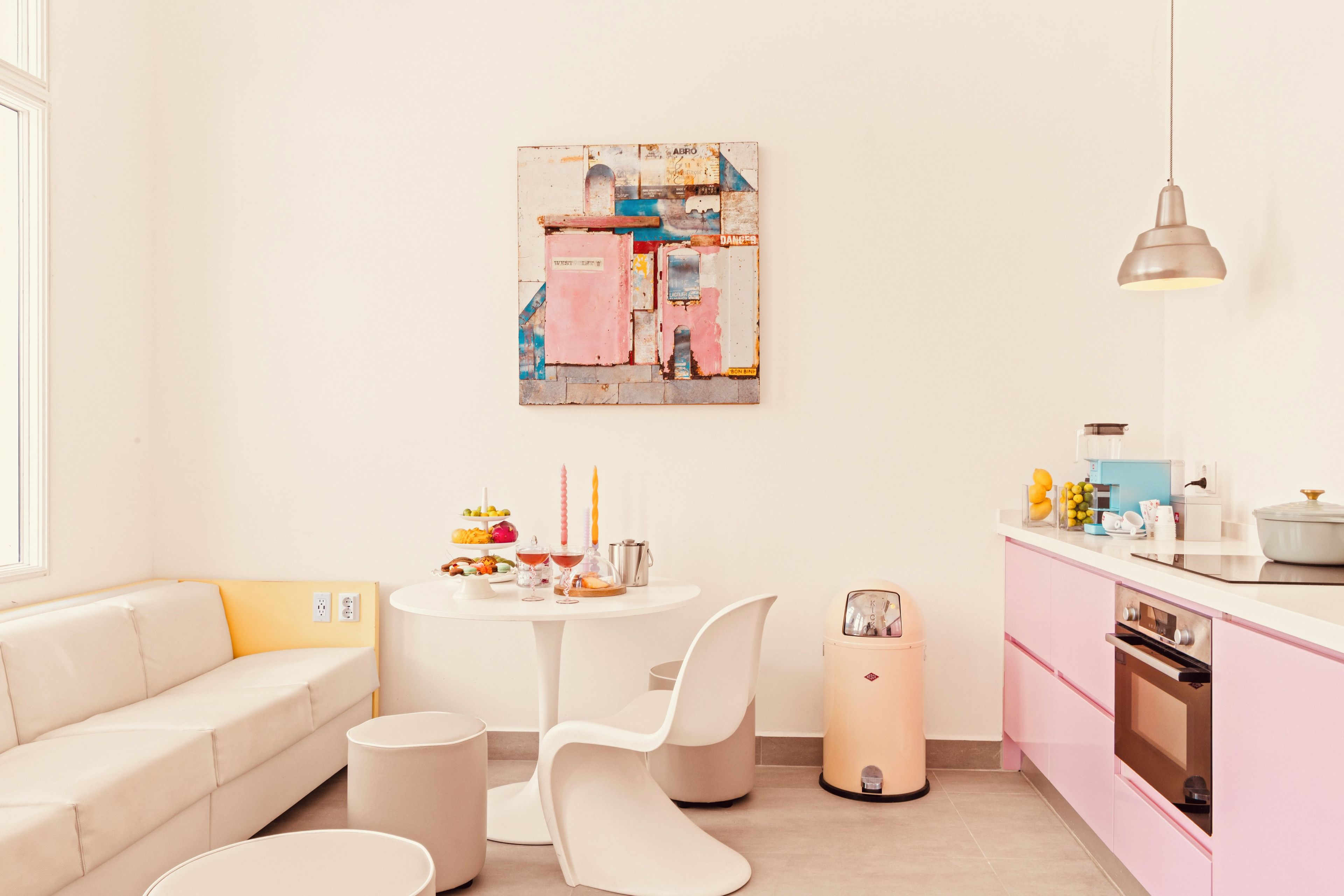 A modern kitchen with pink cabinets, a white dining table, and a minimalist design.