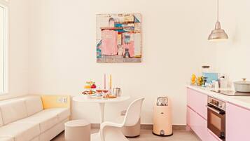A modern kitchen with pink cabinets, a white dining table, and a minimalist design.