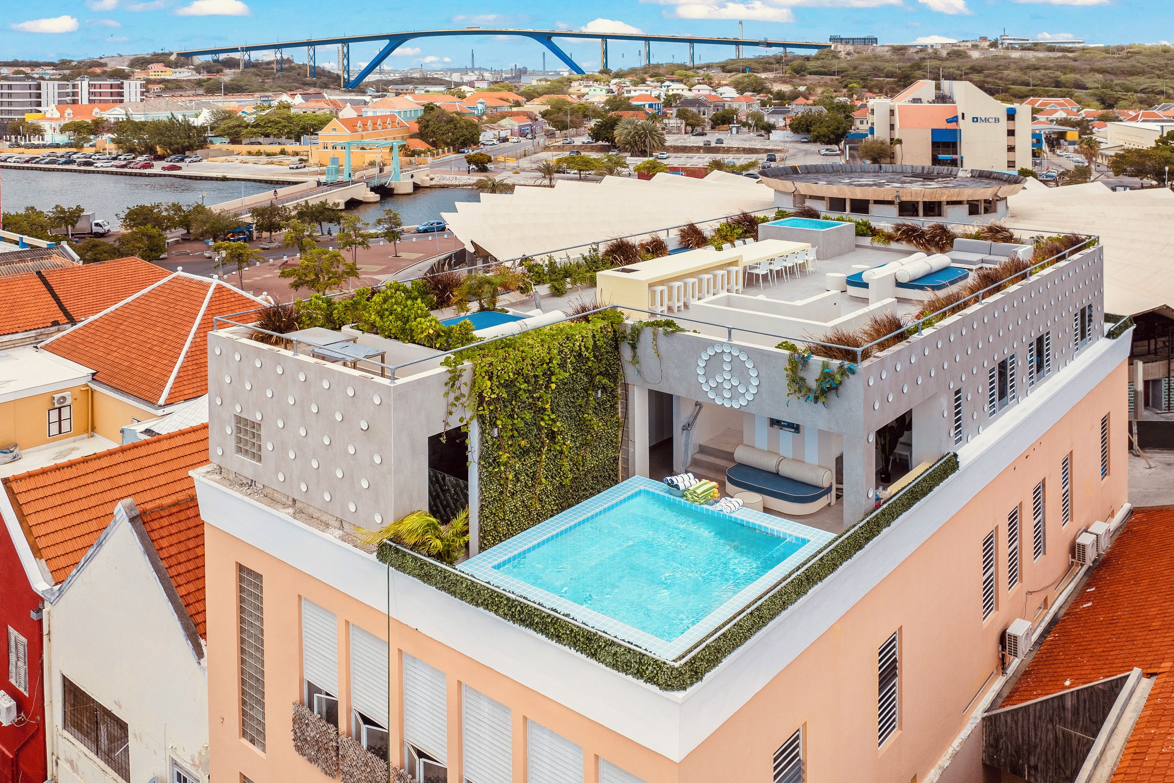 Una piscina en la azotea con vistas al paisaje urbano y un puente al fondo.