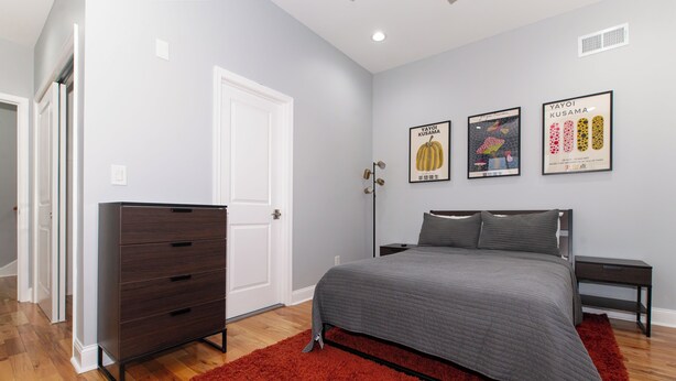 A bedroom with a bed, dresser, and artwork on the wall. - Modern 2BR 2BA Apt - Near Temple University (Philadelphia)