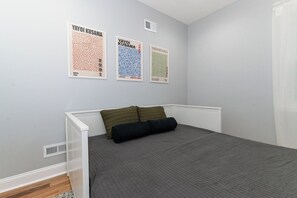 Un dormitorio con una cama, un radiador y tres carteles en la pared.