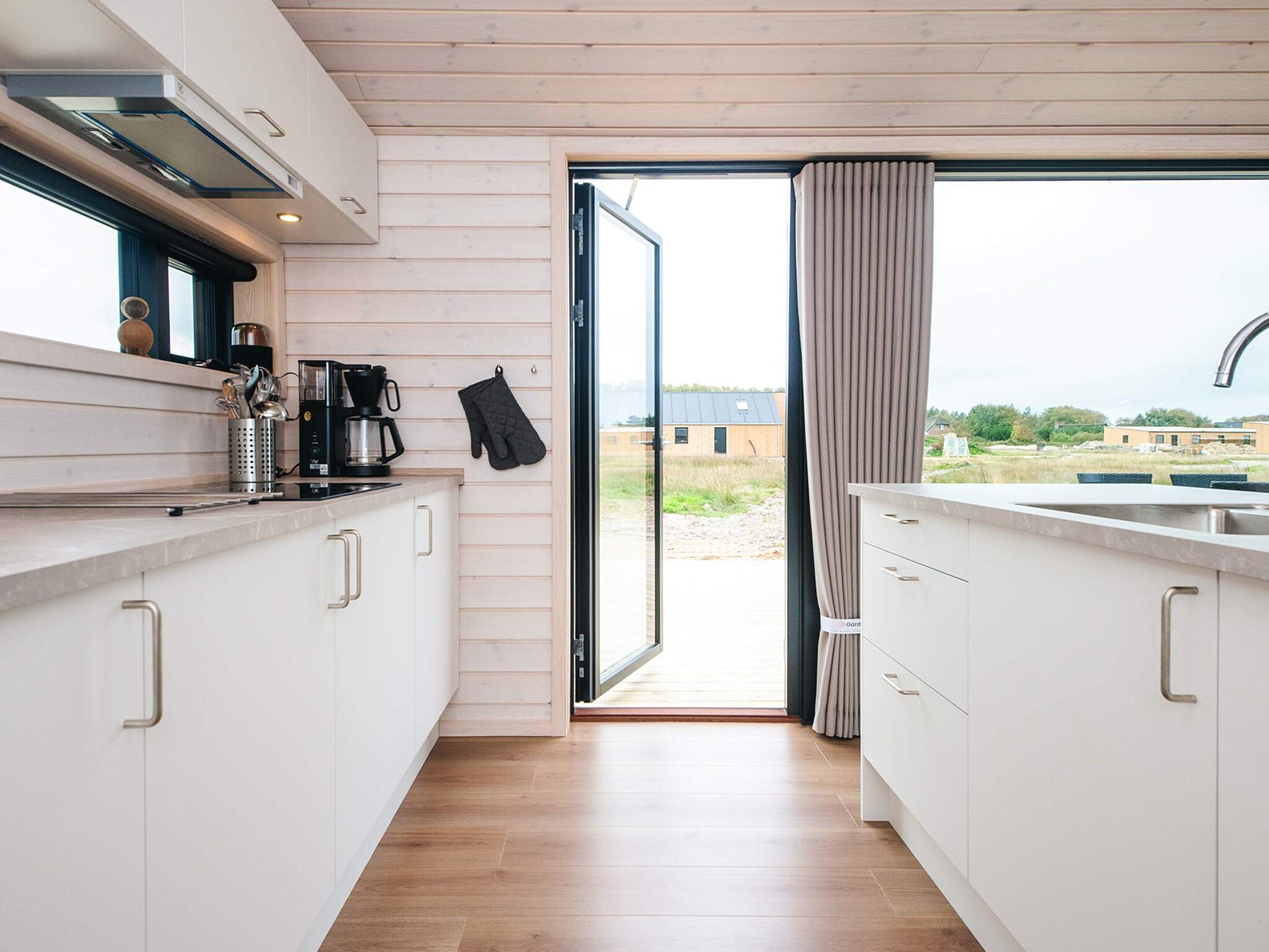 A modern kitchen with white cabinets, a stainless steel sink, and a window overlooking a grassy area.