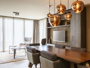 A modern dining area with a wooden table, leather chairs, and pendant lighting. - Apartment in Schruns With Swimming Pool (Schruns)
