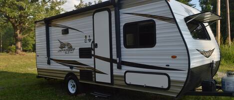 A recreational vehicle with a logo, a side entrance, and a window.