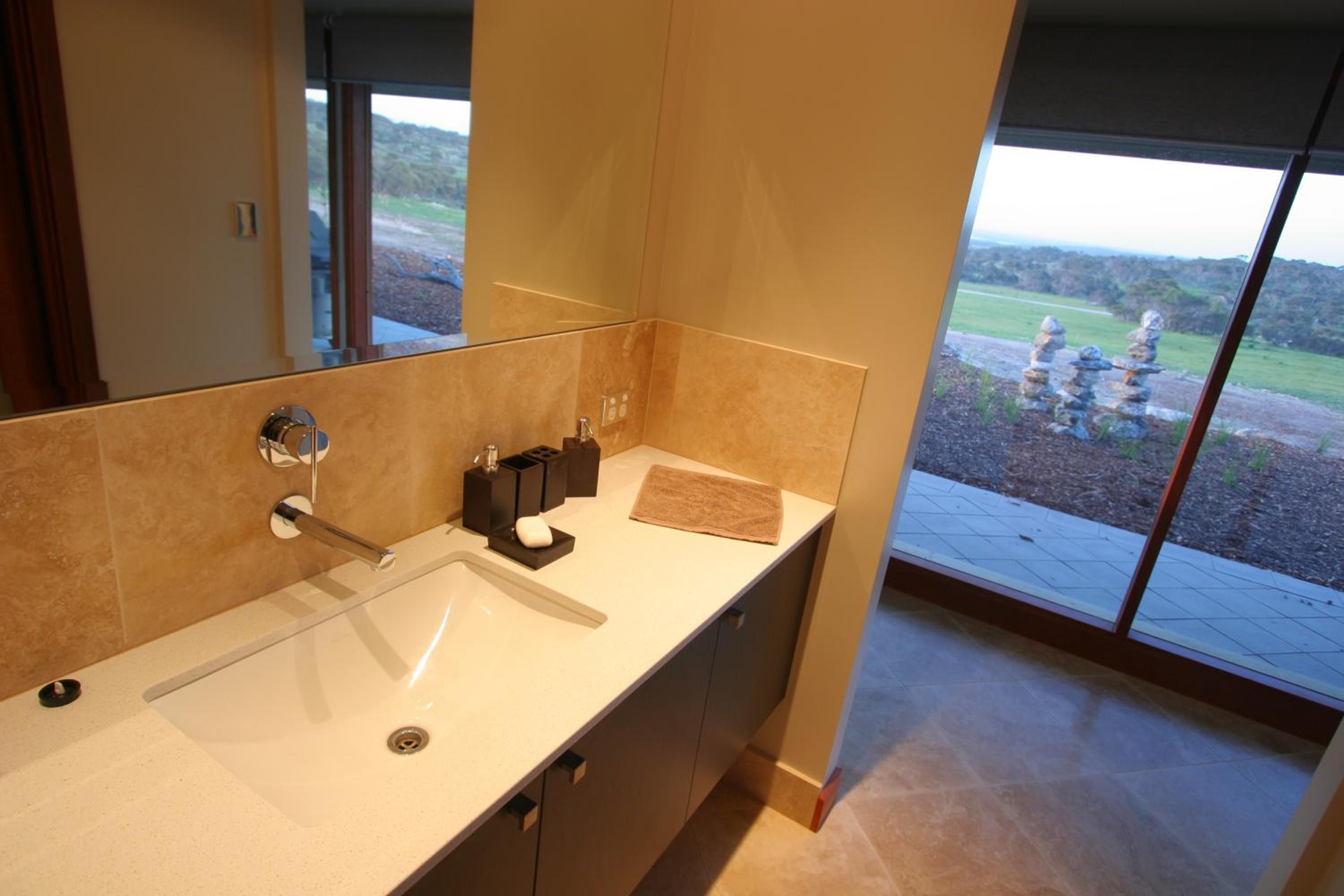 A modern bathroom with a large window, a sink, and a mirror.