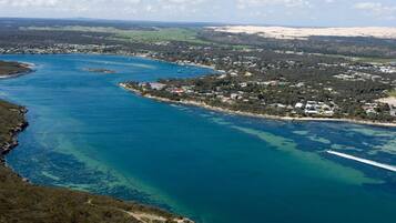 A coastal town with a marina, clear blue waters, and a hilly landscape in the background.